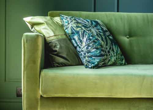 About Department Stores. Green velvet sofa with decorative cushions in a stylish interior, representing EPOS Cubed’s support for department stores and homeware retailers.