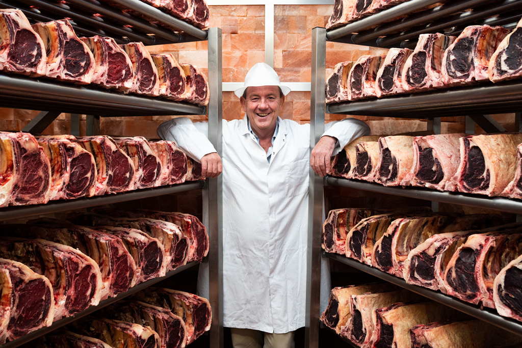 A butcher standing in a Himalayan salt-aged meat chamber, surrounded by racks of dry-aged beef cuts - Storefront EPOS case study