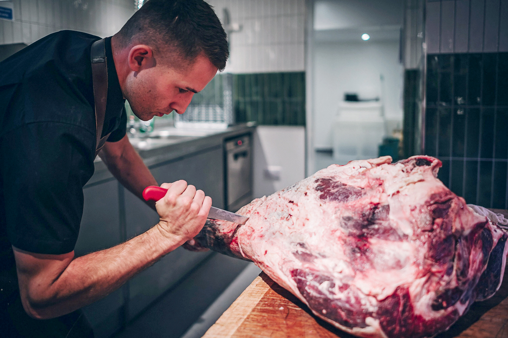 Butcher preparing a large cut of meat at Peterley Manor Farm