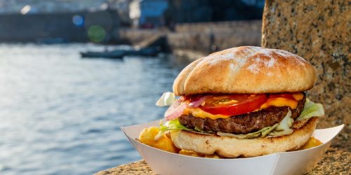 Freshly cooked burger served by Mevagissey harbour with water in the background