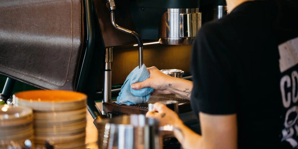 Barista cleaning an espresso machine while preparing coffee at Café 360 on the Isle of Man