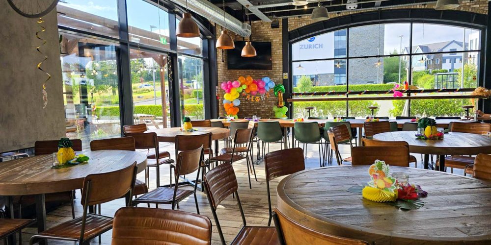 Interior dining area at Café 360 on the Isle of Man with wooden tables and large windows