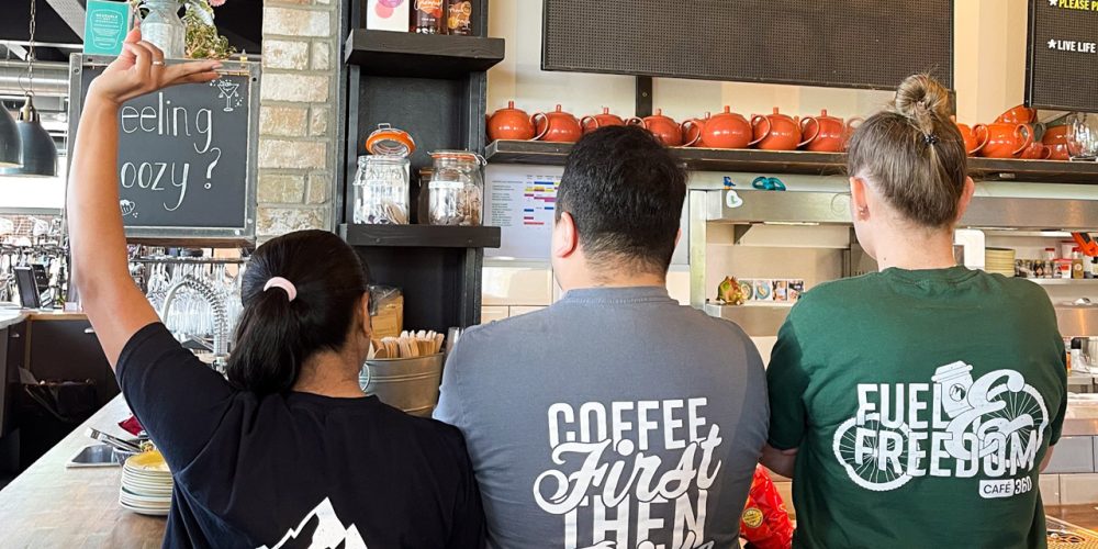 Café 360 team behind the counter wearing branded t-shirts at the Isle of Man café