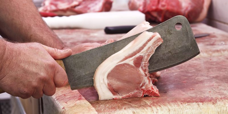 Traditional butcher preparing pork chop at Calcott Hall Farm Shop.