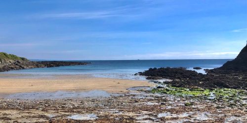 Cornish coastline with sandy beach and rocky shoreline overlooking the sea