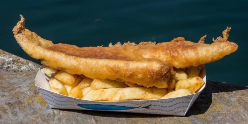 Battered fish and chips served in a tray overlooking the sea at The Fishermen’s Chippy
