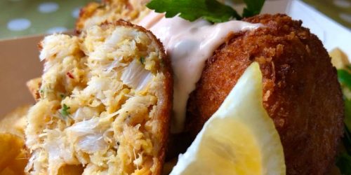 Close-up of a homemade fishcake cut open, showing flaky fish filling with lemon wedge at The Fishermen’s Chippy