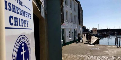 The Fishermen’s Chippy sign on the harbourfront in Mevagissey, Cornwall