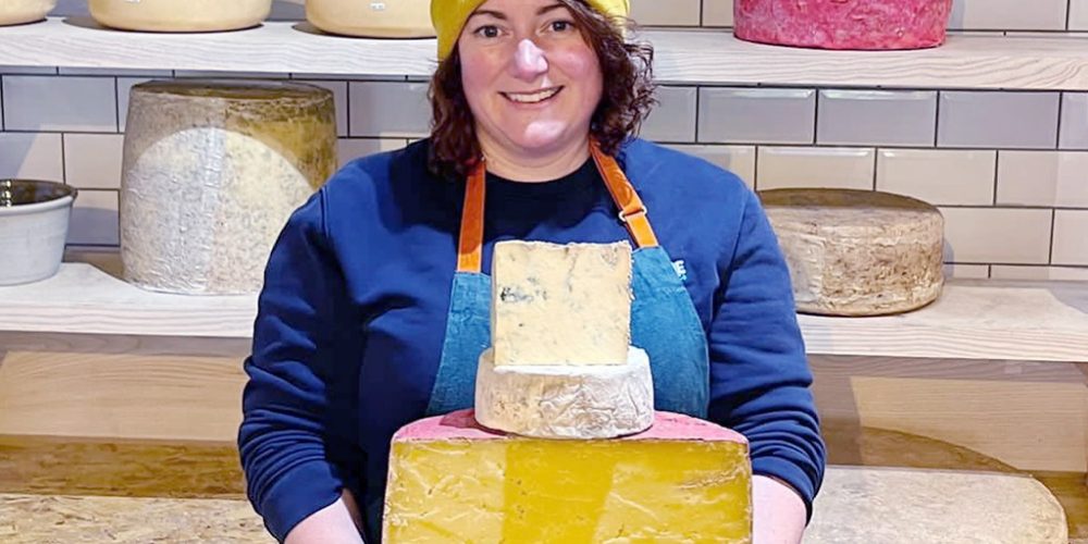 Indie Füde cheesemonger holding artisan Irish cheeses in the Belfast deli and cheese shop.