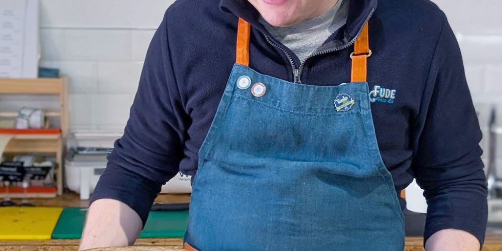 Cheesemonger at Indie Füde preparing artisan Irish cheese in the Belfast cheese shop.
