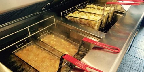 Traditional fish and chip fryer with baskets of chips cooking in hot oil