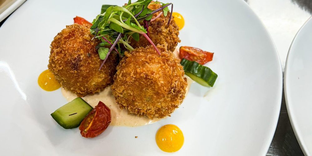 Plated starter dish prepared for an event at Woodbourne House, featuring crispy croquettes with seasonal garnish.