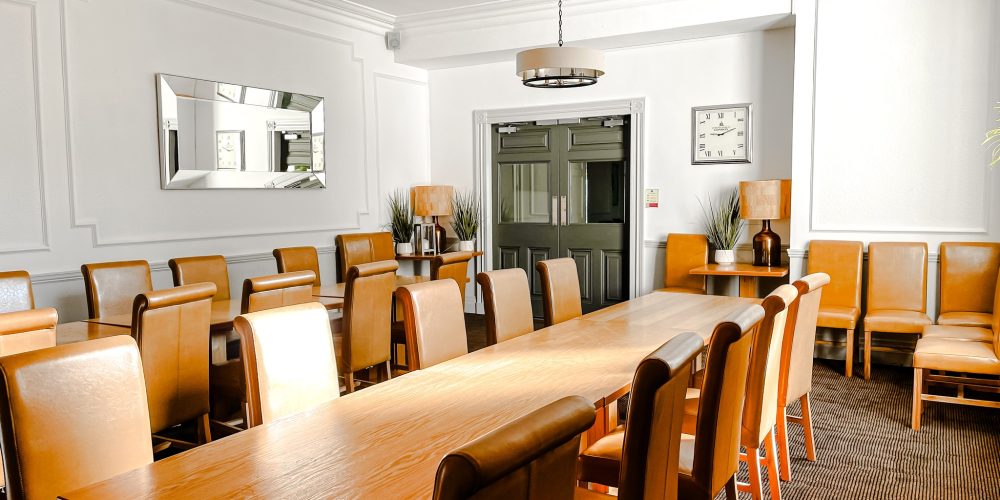 Private dining and meeting room at Woodbourne House with long wooden table and leather chairs.