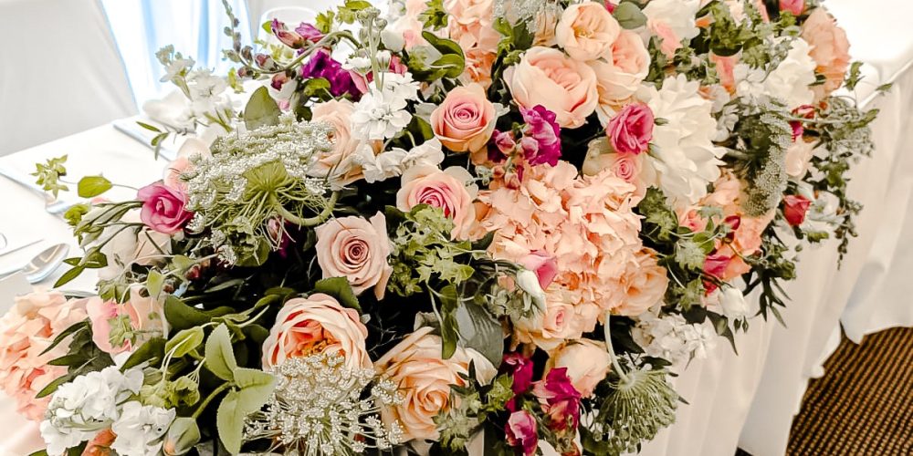 Floral arrangement on the wedding top table at Woodbourne House with blush roses and greenery.