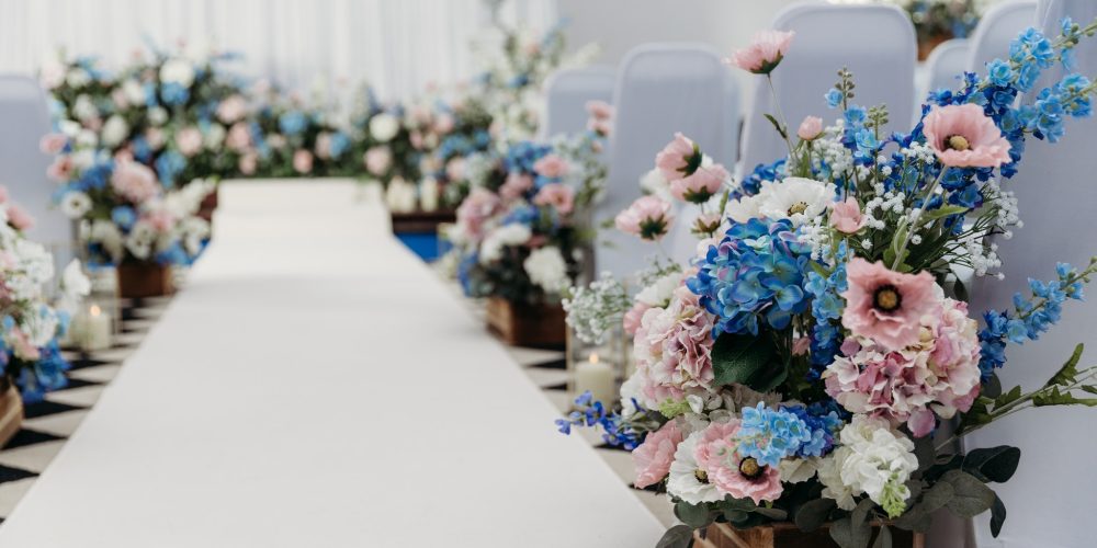 Wedding ceremony aisle at Woodbourne House decorated with pastel floral arrangements in wooden boxes.