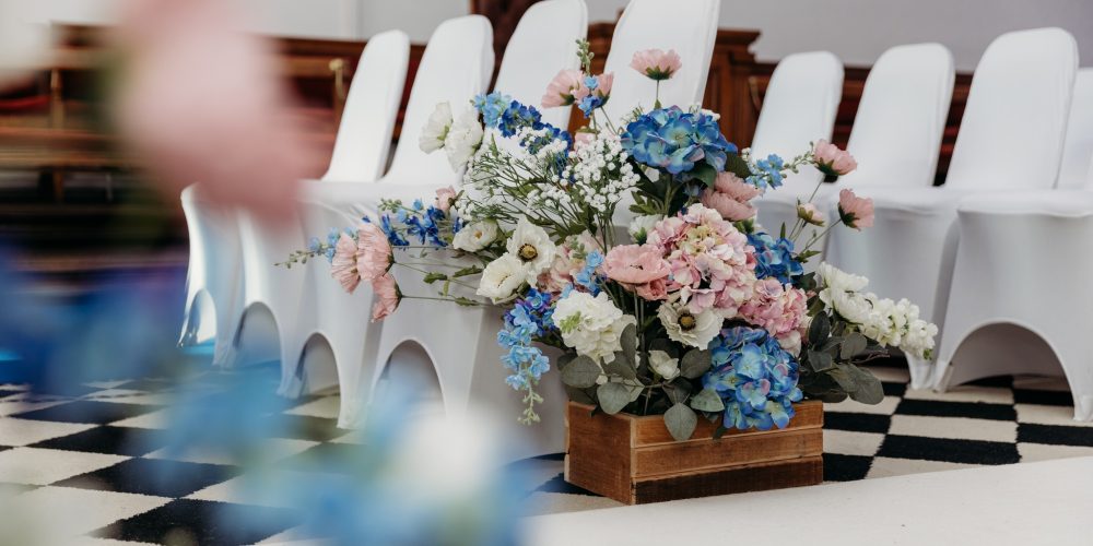 Floral arrangement beside ceremony seating at a wedding hosted at Woodbourne House on the Isle of Man.