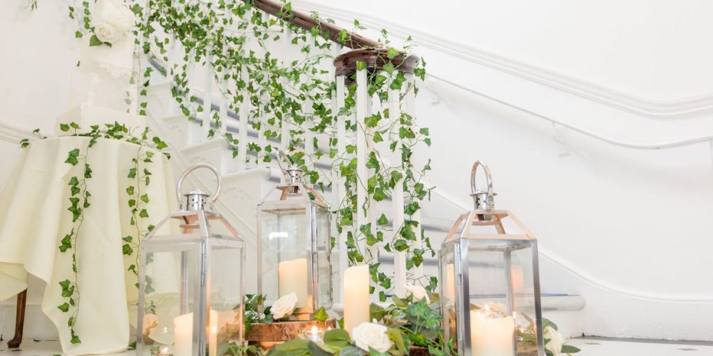 Elegant wedding décor with candles and greenery on the staircase at Woodbourne House, an Isle of Man wedding and events venue.
