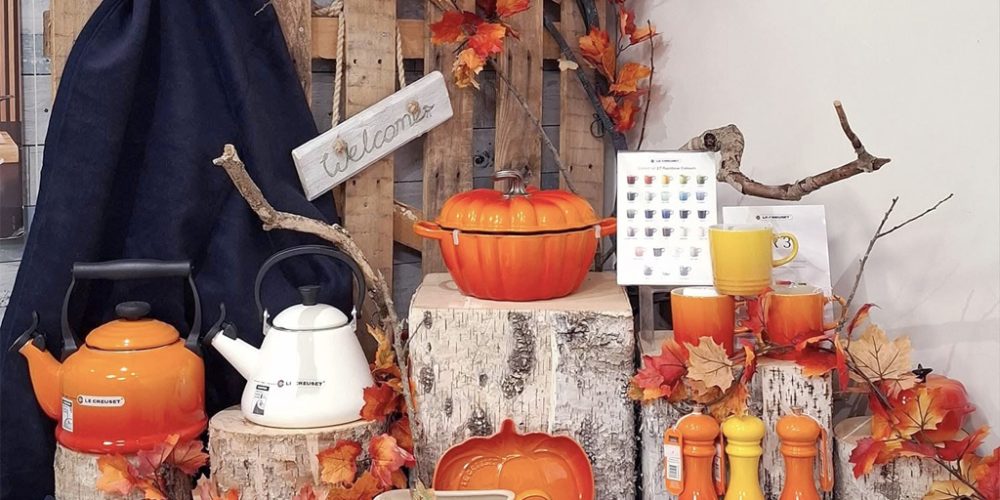 autumn themed kitchenware display with orange cookware and seasonal decor