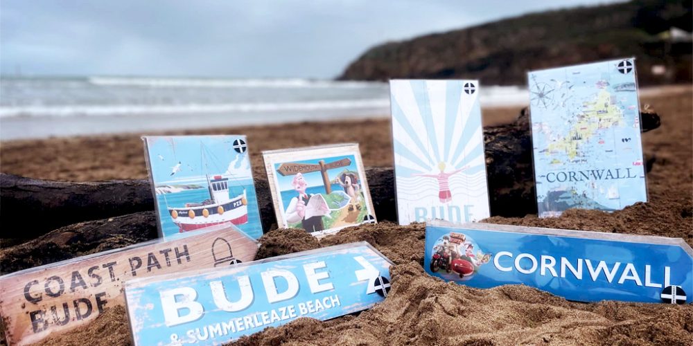 Coastal-themed gift items and Cornwall souvenirs displayed on a beach, available at Wroes department store.