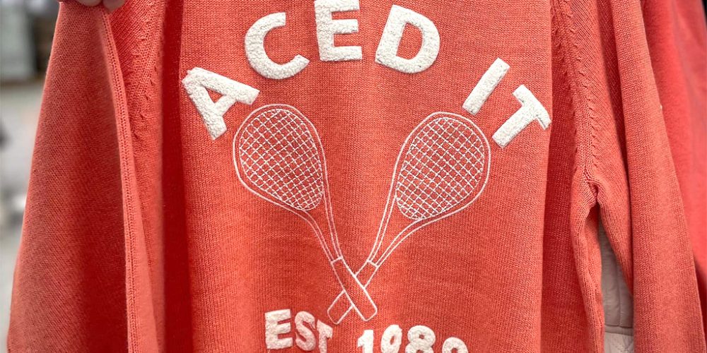 orange jumper with tennis graphic and est 1989 text